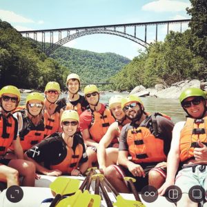 Group of HGC employees smiling while whitewater rafting