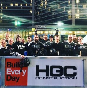 Team of athletes stand behind HGC Construction sign