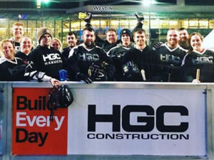 Team of athletes stand behind HGC Construction sign