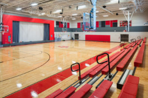 School gymnasium with bleachers open and basketball hoops lowered