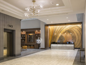 Grand foyer and lobby of a hotel with a dramatic mosaic behind the hospitality desk