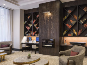 Hotel lounge with dark wooden shelves with books and neutral arm chairs