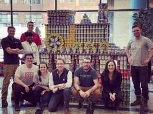 Team in front of train sculpture made of cans