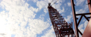 crane reaching into the blue sky speckled with clouds